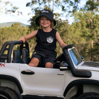Child sitting in a toy car outdoors with trees in the background wearing Cobba country Tank and Bucket Hat